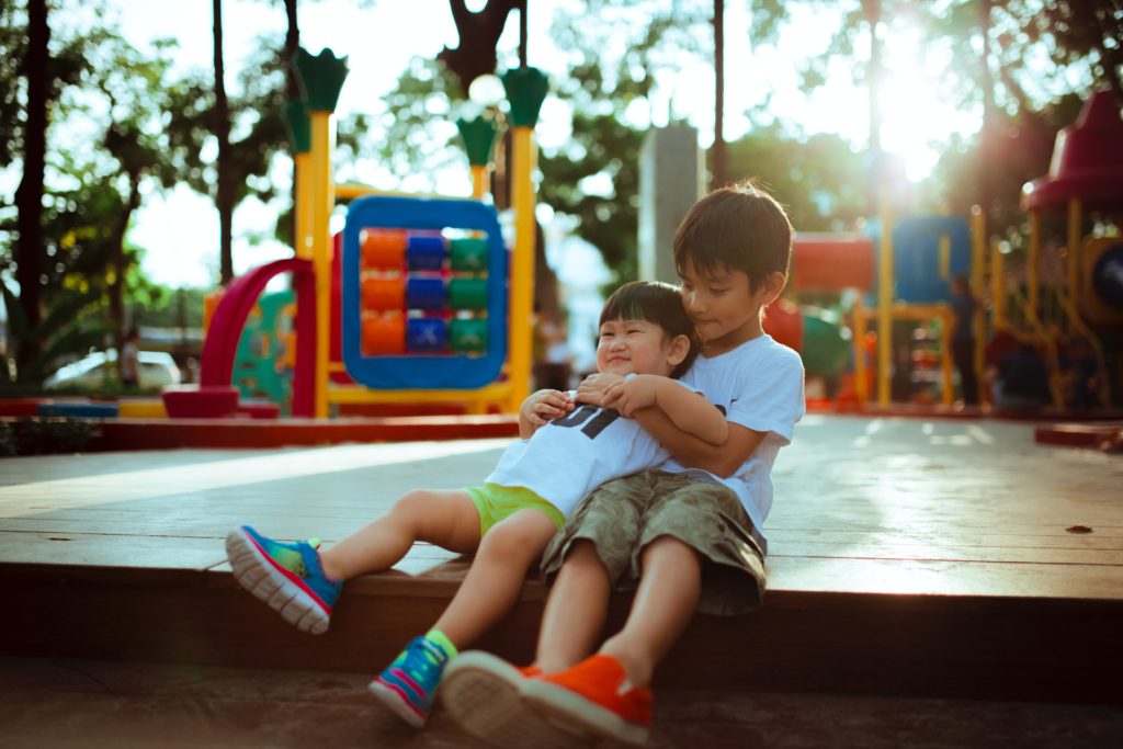 A boy playing with his younger brother at a playground.