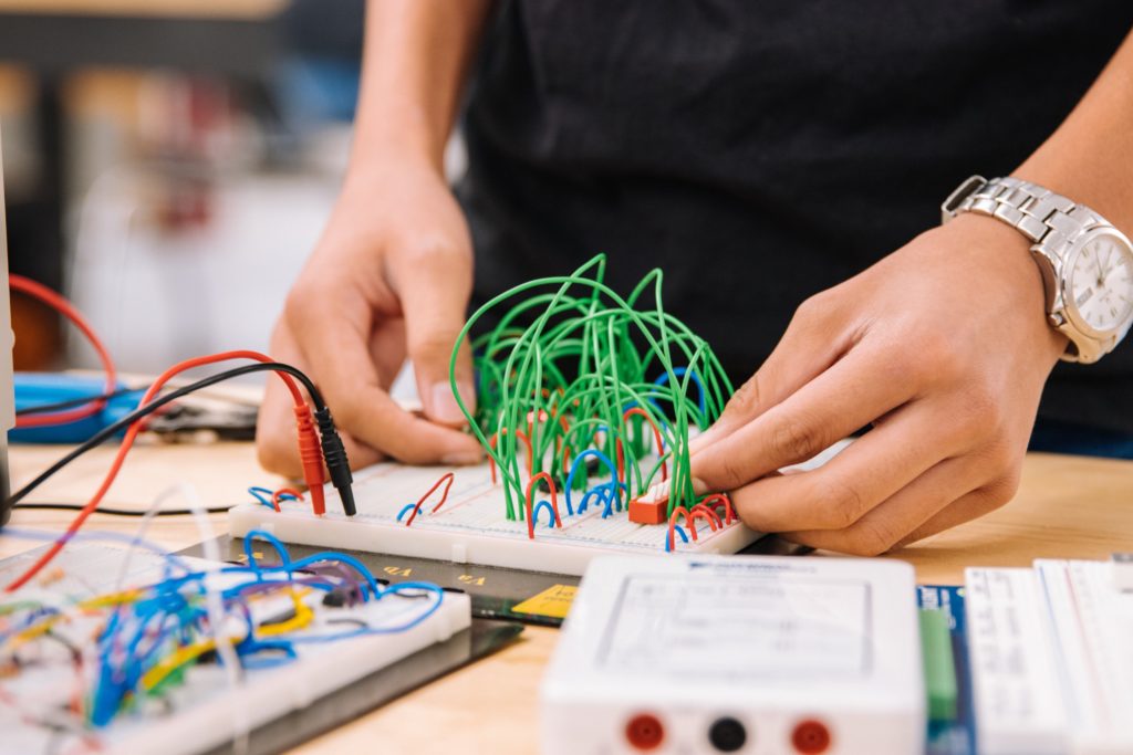 A photograph of someone working on a breadboard circuit. Only their hands are visible.